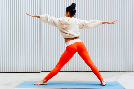 Female athlete standing in warrior position in front of wall