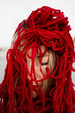 Woman covering face with red thread