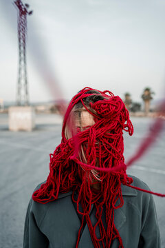 Woman covering face with red thread on road