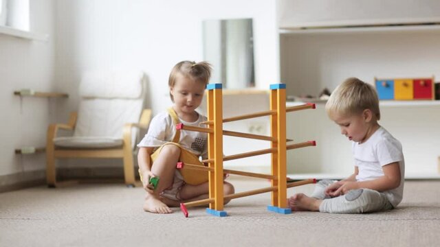 Toddlers children play with natural wooden toys on the floor in a bright room, activities in the children's center with montessori materials and educational toys, sensory development
