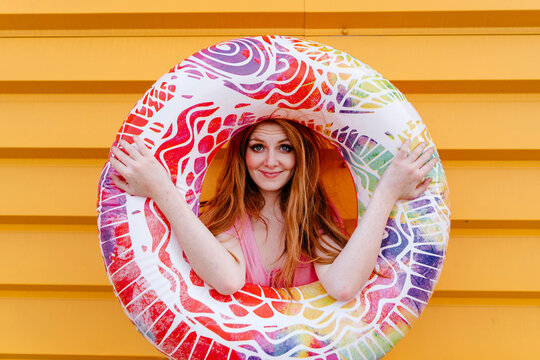 Smiling woman holding inflatable tube in front of wall