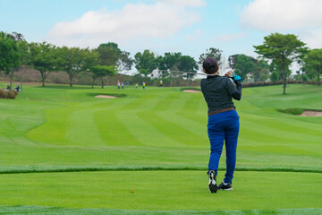 Obraz premium woman Golfer Hitting Ball with Club on Beatuiful Golf Course