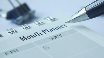 hand hold a pen pointing on monthly planner text on calendar 