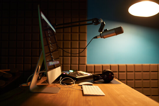 Computer with microphone and headphones placed on table in podcast studio
