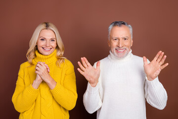 Portrait of two attractive cheerful lucky grey-haired people good news reaction isolated over brown color background