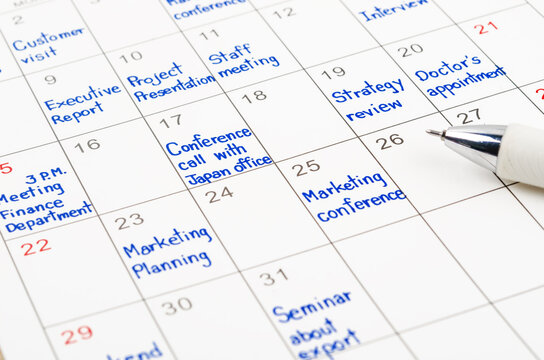 Handwriting scheduling appointments on calendar sheet.