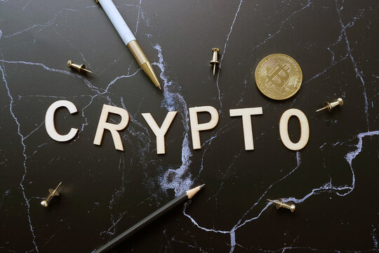 Flatlay wood text crypto with pen and coin on 
desktop background.for Crypto currentcy concept.
