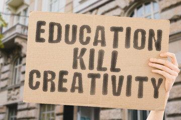 The phrase " Education kill creativity " on a banner in men's hand with blurred background. University. School. System. Dangerous. Study. Students. Knowledge. Occupation