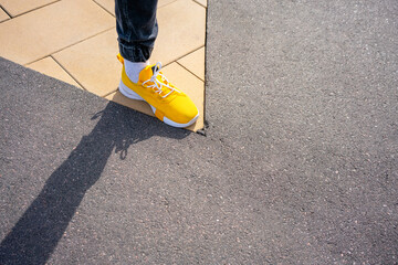 Boy wearing yellow shoe while standing on footpath