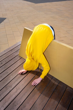 Boy bending on wooden bench