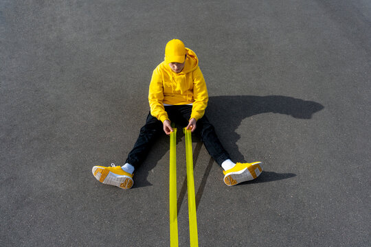 Boy holding yellow adhesive tapes while sitting on road