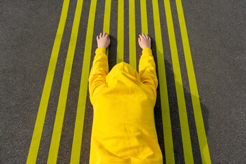 Boy lying on road with parallel yellow markings