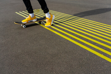 Boy riding skateboard on road with parallel yellow markings