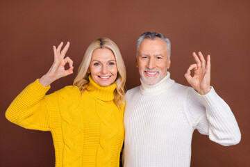 Photo of funky blond aged lady beard man show okey wear yellow white sweaters isolated on brown color background