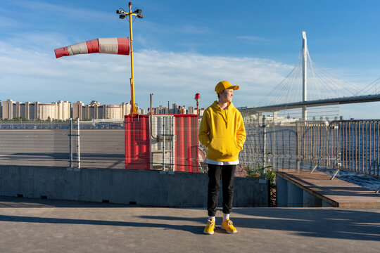 Boy looking away while standing on road during sunny day