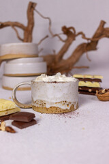 A cup of cocoa with cream and chocolate on a light background