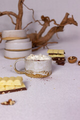 A cup of cocoa with cream and chocolate on a light background