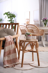 Fototapeta na wymiar Stylish wooden stool with bouquet of flowers near armchair in room. Interior element