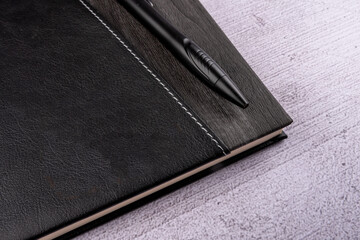 Top view of notebook and pen on gray background.
