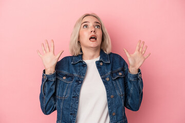 Young caucasian woman isolated on pink background screaming to the sky, looking up, frustrated.