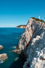 Ionian sea island steep rocky cliffs with lighthouse on top. Bright blue sky summer day in Greece. Scenic travel destination. Lefkada island. Vertical