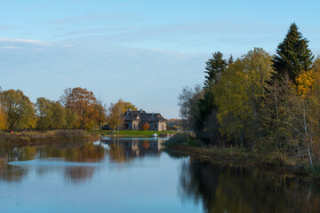 Fototapeta na wymiar A beautiful lake with a blue sky and a birch grove by the mill pond