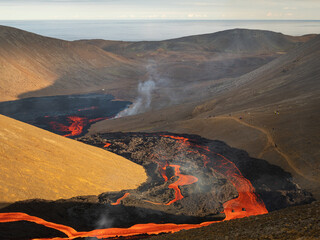 Volcanic eruption. Fresh hot lava, flames and poisonous gases going out from the crater.