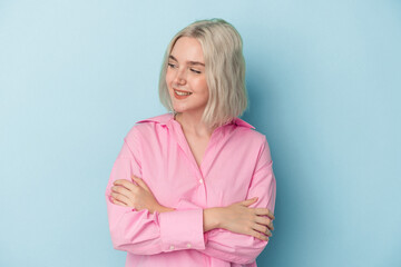Young caucasian woman isolated on blue background smiling confident with crossed arms.