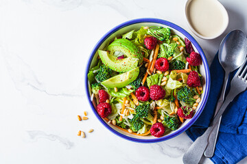 Green broccoli salad with raspberries, pine nuts and avocado. Vegan food concept.