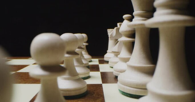 White chess pieces are lined up in even rows on a game board, ready for game