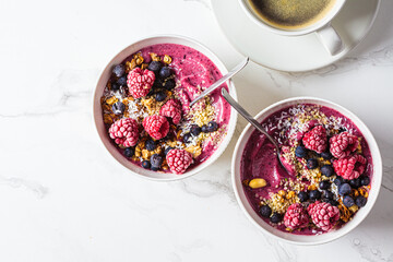 Berry smoothie bowl with granola, coconut and hemp seeds, marble background. Vegan food concept.