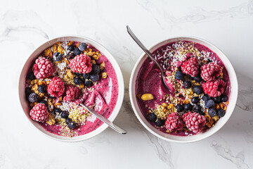 Berry smoothie bowl with granola, coconut and hemp seeds, marble background. Vegan food concept.