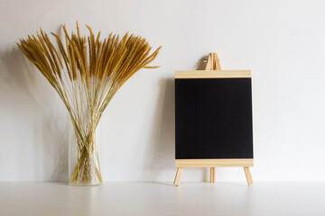 A blackboard with brown organic flowers in a vase with nature light.  © aradaphotography