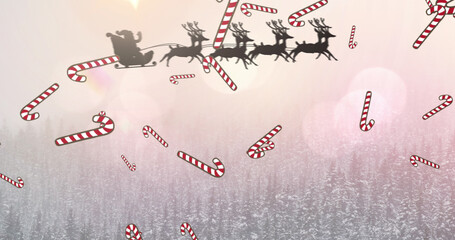 Image of candy canes and santa in sleigh over christmas winter scenery