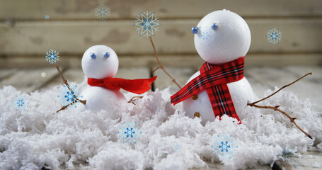 Image of snow falling over snowmen at christmas