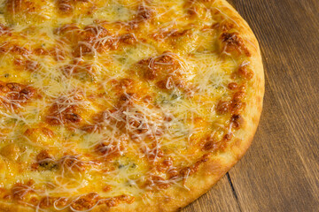 Baked pizza with cheese on a wooden background