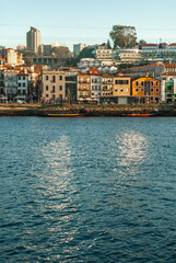 Fototapeta na wymiar Porto, Portugal - September 18, 2021: Colorful embankment of Gaia with wine cellars sun glade reflection on the river Douro waters european style houses