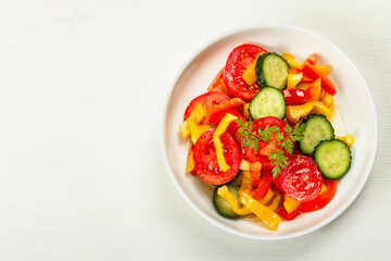 Seasonal fresh vegetable salad with ripe tomatoes, cucumbers, bell peppers