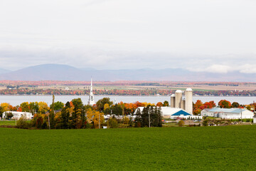 Fototapeta na wymiar Picturesque village with the St. Lawrence River and the Laurentian mountains in the background seen during a beautiful Fall morning, St. Michel-de-Bellechasse, Quebec, Canada