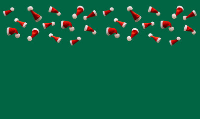 red Christmas hats on a green background, creative concept of Christmas with free space for text