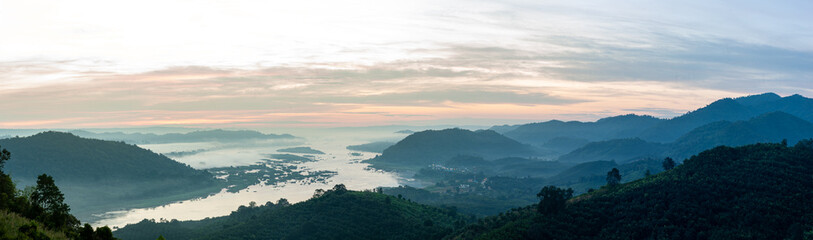 Obraz premium A large river flows through the mountains at dawn.