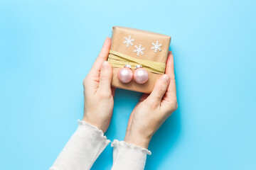 Hands holding gift box decorated with Christmas balls and snowflakes. Christmas and New Year present preparation
