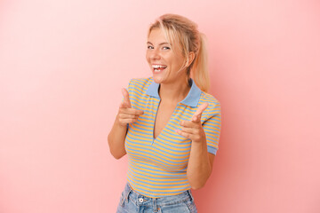 Young Russian woman isolated on pink background cheerful smiles pointing to front.