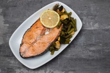 fried salmon with fresh lemon and spinach on white dish