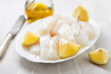 raw squid with pepper and fresh lemon on white dish