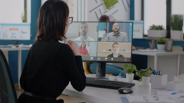 Corporate worker talking to colleagues on video call for business project. Woman using online conference on computer for marketing strategy and planning with team of corporate workmates