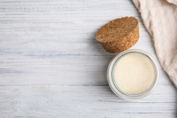 Gelatin powder in glass jar on white wooden table, flat lay. Space for text