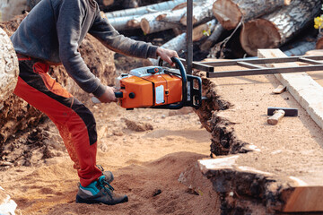 Closeup of lumberjack cutting tree trunk with giant chainsaw to make wooden planks