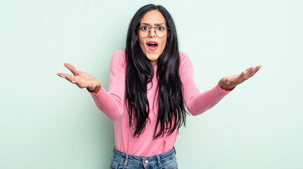 pretty hispanic woman feeling extremely shocked and surprised, anxious and panicking, with a...