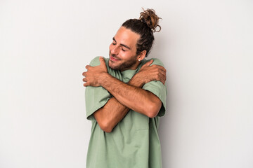 Young caucasian man isolated on gray background hugs, smiling carefree and happy.